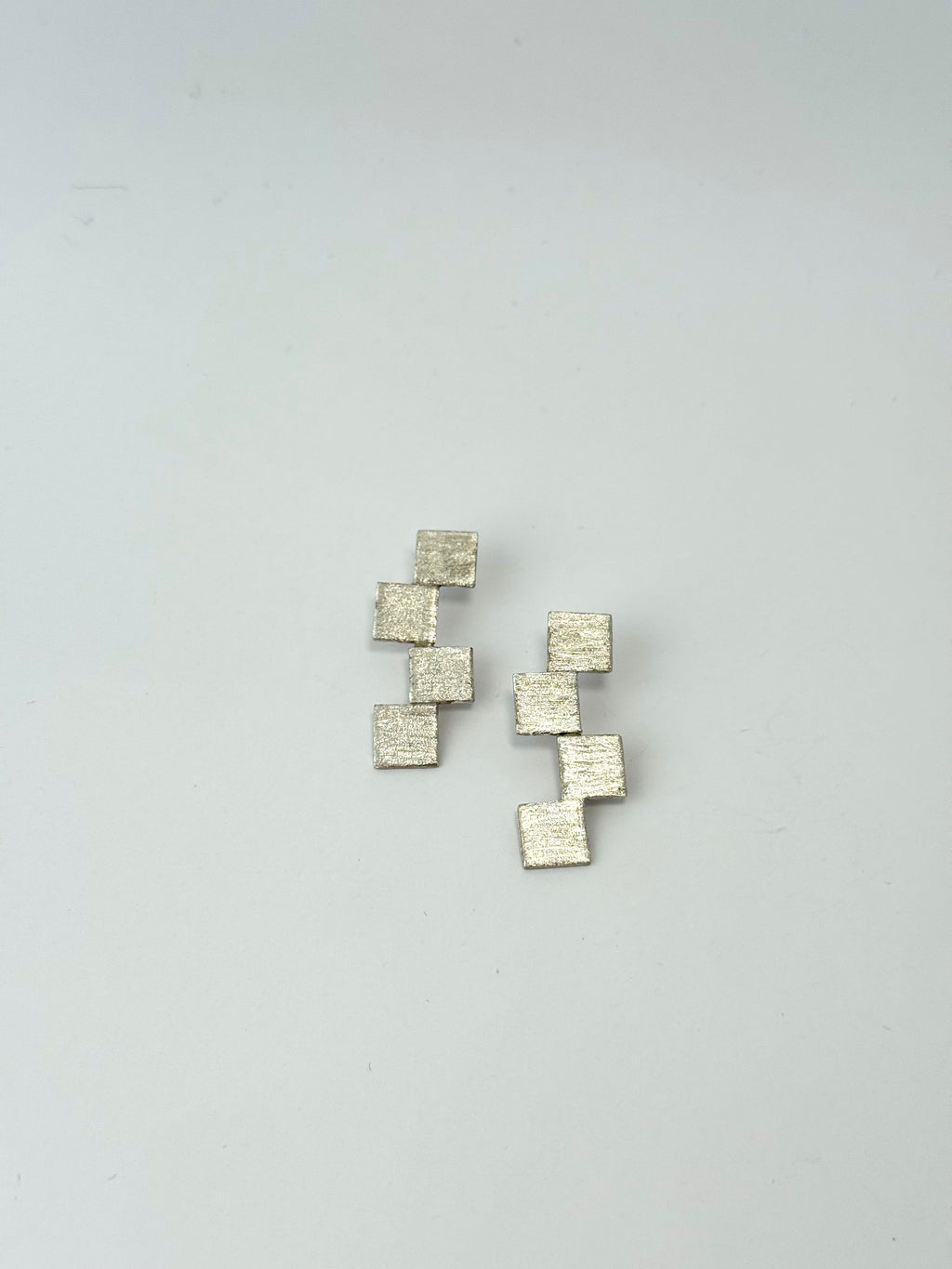 Set of square-shaped earrings on a light gray background